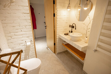 Stylish bathroom with brick walls painted in white and sink on tiled table top