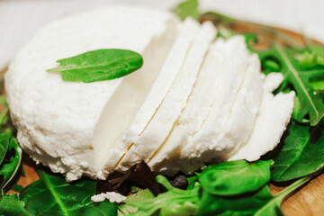 suluguni pickled cheese on a wooden board with herbs.