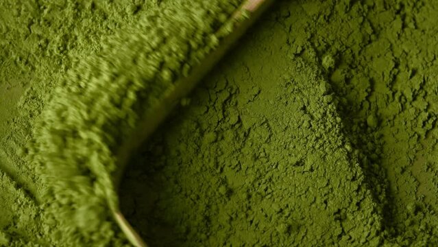 Matcha green tea powder mixing with a spoon