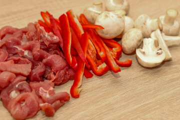 Sliced meat, champignons and red pepper on a board.
