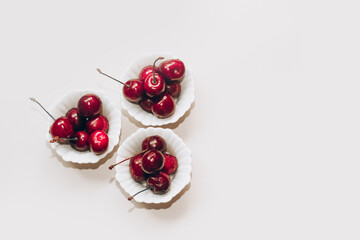 Ripe red cherries in white plates on the table.