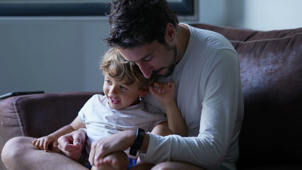 Candid father and son relationship at home. Dad holding kid in lap. Authentic real life fatherhood...