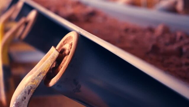 Rotating conveyor belt wheel. Clay stones moving in background out of focus. Slow motion 25perc. 4k.