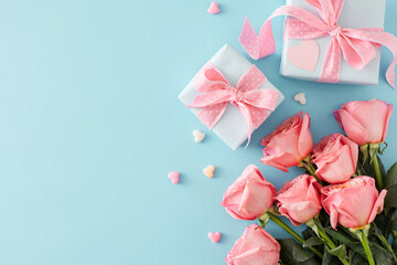 Present concept for Mother's Day. Top view photo of present boxes with bows bouquet of pink roses and small hearts baubles on isolated pastel blue background with copy space