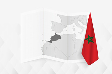 A grayscale map of Morocco with a hanging Moroccan flag on one side. Vector map for many types of news.