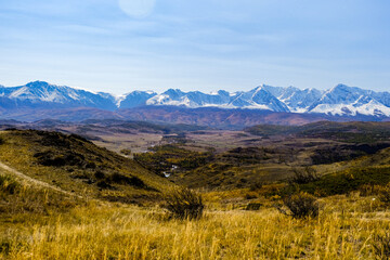Autumn yellow landscape of the valley desert in front of majestic snow-capped high mountains. Kurai...