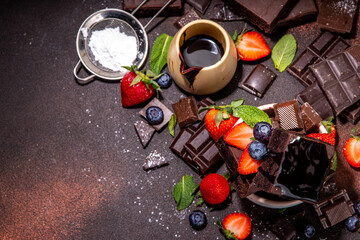 Dark chocolate brownies with berries. Stack of homemade brownie cake cookies with chocolate sauce drizzled on it and fresh strawberry, blueberry, on dark background copy space