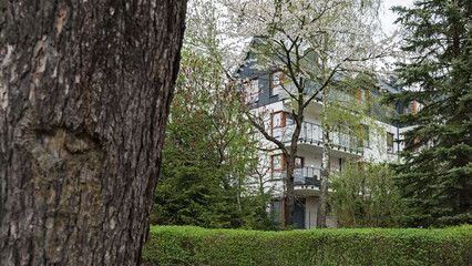 Detal na elewacje i balkony w nowoczesnym budynku wielorodzinny w europejskim mieście. Ciekawa architektura. Wśród roślinności i drzew. Kwitnąca wiosna