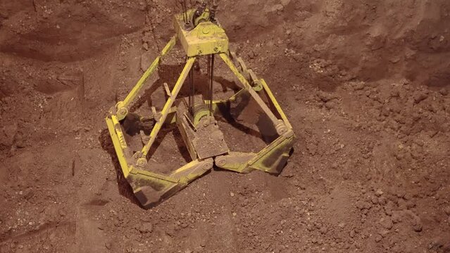 Follow shot of clamshell bucket getting clay. 4k.