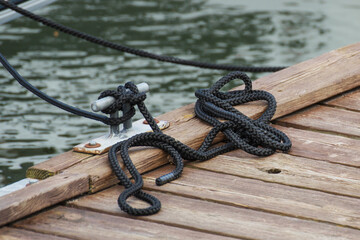 Black rope on bridge as part of yacht anchor. Detail of sailboat