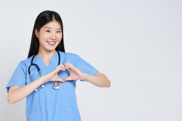 Portrait of smiling young woman doctor makes a heart shape with her hand isolate on white background.