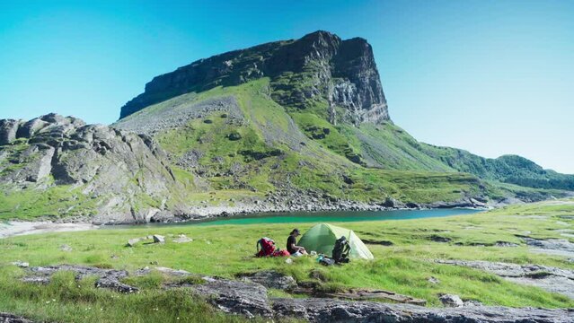A Woman On Campsite Near River Mountains In Lovund, Norway. Wide Shot