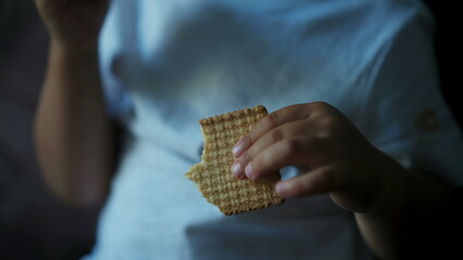 Closeup child hand holding cookie biscuit. Kid snacking bitten dessert