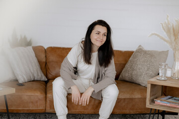 Dunkelhaarige Frau, 40, sitzt gemütlich Zuhause auf der Couch