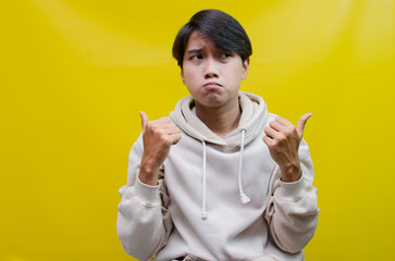 Thoughtful asian man in beige hoodie thinking and wondering with hand touching, rubbing head and...