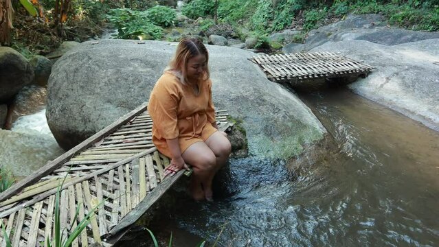 Asian fat woman Tourist stiing on bamboo bridge handmade at vacation holiday natural waterfall. Tourism travel and vacation concept