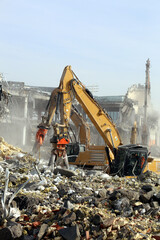 Fototapeta premium Hydraulic excavator demolishing old building. Heavy machinery