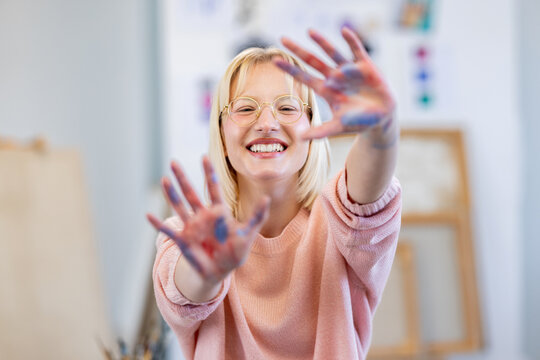 Young woman at art studio smiling, making frame with hands and fingers with happy face