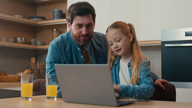 Parental control Caucasian father teaching little daughter using laptop app at home kitchen dad explain computer software help with e-learning online browsing child kid girl happy family with juice