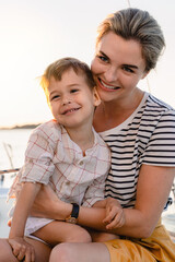 Attractive mother with her adorable toddler son sailing in sea on sailboat