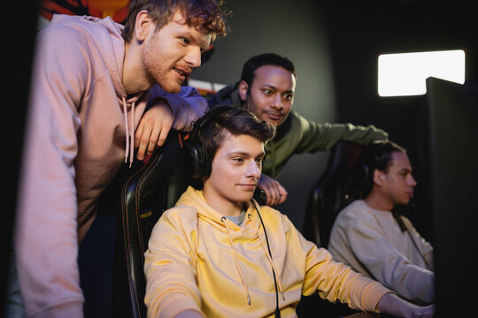 Young Man Playing Video Game On Computer Near Multiethnic Friends In Gaming Club.