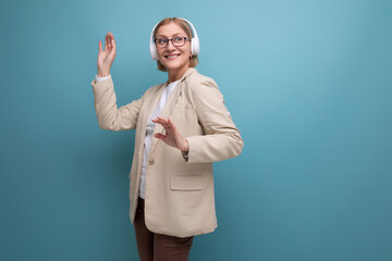portrait of a middle-aged woman in a jacket enjoying music in headphones on a studio background