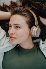 Portrait of young woman listening music trough headphones.