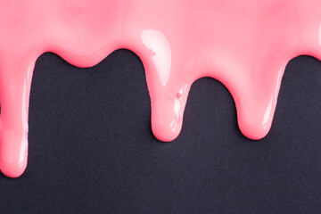 Pink liquid drops of paint color flow down on black paper. Abstract art. Pink paint dripping on the black wall