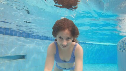 Cute little girl with swimming underwater in a pool