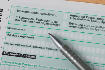 Close Up of filling out a tax declaration with a calculator, a hand with a pen and a piggy bank