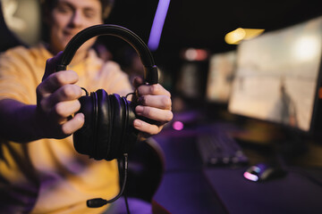 Blurred man holding headphones with microphone in gaming club.