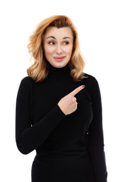 Portrait of forty year old woman grimace on her face and pointing finger to the side, isolated on white background. Woman in black turtleneck with sarcasm on her face posing in studio.