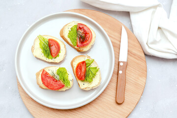 Bruschetta sandwich bread toast with soft white cheese ricotta,fresh tomatoes,basil greenery on a wooden cutting board.Tasty healthy vegetarian food,Italian cuisine appetizer. top view flat lay