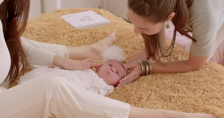 Two young women look at a newborn baby girl. Baby's first days at home. Couple has won the right to adopt a child. 17.09.2022 Konevova, Prague, CZ