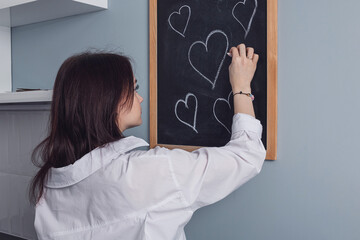 A young girl draws hearts with chalk.