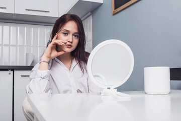 A young girl sits at a table in front of a mirror.