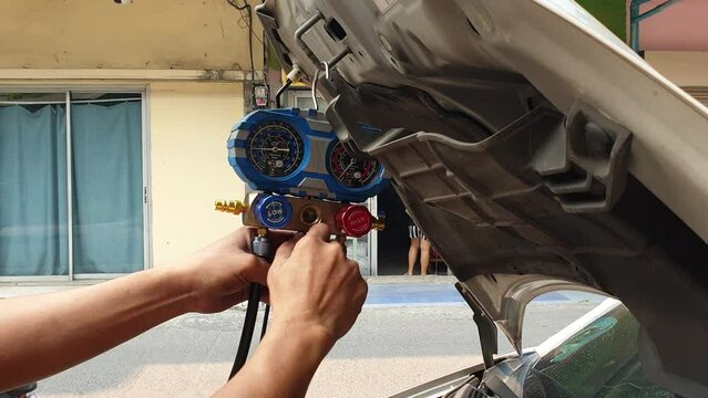 Repair man checking for air AC compressor cooling system leaking suspect auto shop check pressure