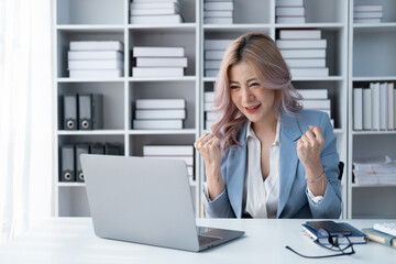 Happy Asian businesswoman feeling overjoyed after hearing a good news from company.