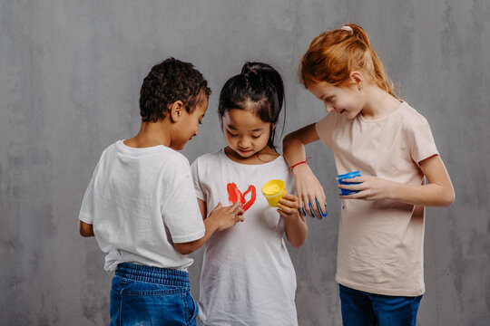 Portrait of happy kids with finger colours and painted hands.