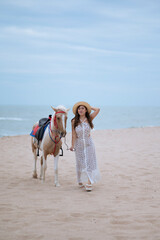 Young long hair woman in white dress riding horse on seascape background