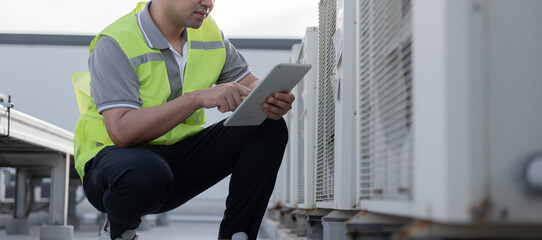 Obraz premium Asian maintenance engineer works on the roof of factory. contractor inspect compressor system and plans installation of air condition systems in construction. technology, online checking