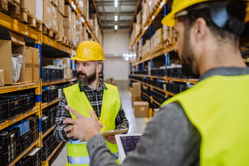 Warehouse workers checking stuff in warehouse with digital system in tablet.