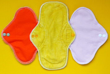 Bamboo washable sanitary napkins. Three colorful eco reusable menstrual pads on yellow background. Women hygiene concept, eco-friendly fabric pads, zero waste pads alternatives.