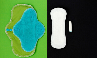 Two green bamboo washable sanitary napkins on green background vs a disposable panty liner and a tampon on black background. Sustainable life concept, zero waste concept. Saving money concept.