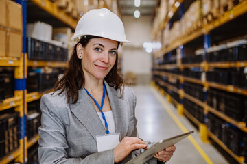 Manager woman in suit controlling goods in a waehouse.