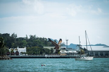 Boats in the sea and the Big Eagle statue in Langkawi island, Malaysia.