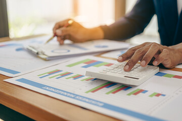 accountant working on desk using calculator for calculate finance report in office Business accounting concept, Business man using calculator with computer laptop, budget and loan paper in office.