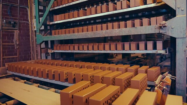 Brick production line. Fresh clay bricks being put on shelves for drying. 4k.