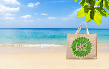 Jute bag with No plastic banner on tropical beach, summer outdoor day light