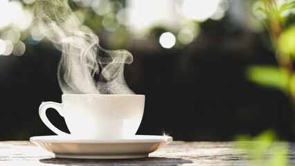 Naklejka na ściany i meble Coffee Cup. Close-up natural steam smoke of coffee from hot coffee cup on old wooden table in morning warm sunshine flare, outdoor view background. Concept hot drink, espresso, breakfast